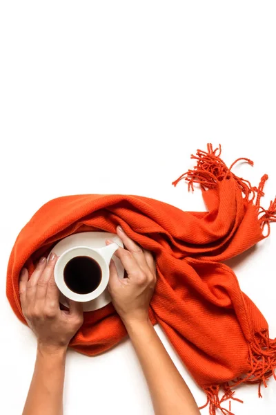 Xícara de café envolto em um cachecol cinza e as mãos femininas em um fundo branco é isolado. Conceito de outono ou inverno. Deitado plano, vista superior — Fotografia de Stock