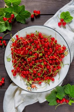 Rustik tarzı bir düz ahşap arka plan üzerinde beyaz metal bir kase içinde Frenk üzümü meyveler üstten görünüm bir kopya alanı ile yatıyordu.