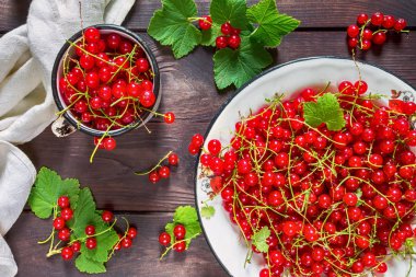 Rustik tarzı bir düz ahşap arka plan üzerinde beyaz metal bir kase içinde Frenk üzümü meyveler üstten görünüm bir kopya alanı ile yatıyordu.