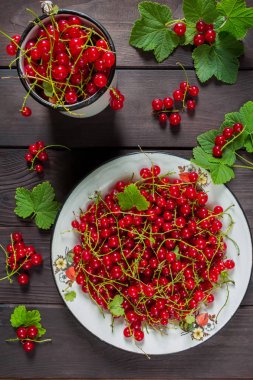 Rustik tarzı bir düz ahşap arka plan üzerinde beyaz metal bir kase içinde Frenk üzümü meyveler üstten görünüm bir kopya alanı ile yatıyordu.