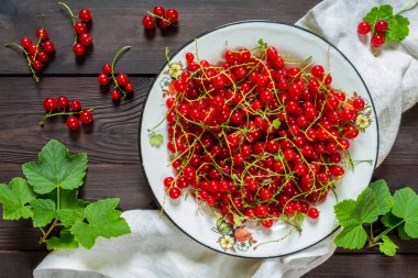 Rustik tarzı bir düz ahşap arka plan üzerinde beyaz metal bir kase içinde Frenk üzümü meyveler üstten görünüm bir kopya alanı ile yatıyordu.