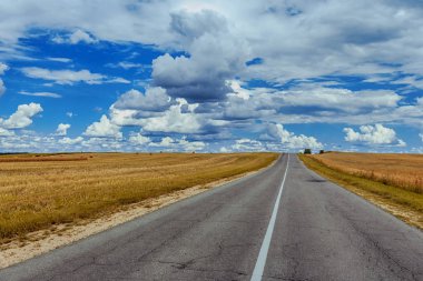 Alanıyla buğday ve yığınlar, yol mavi gökyüzü bulutlu bir yaz gününde