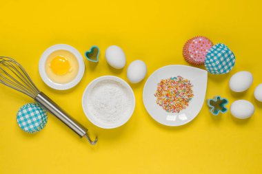 Paskalya fırınkavramı, ev pişirme için çeşitli ürünler, şeker, yumurta ve un, hindistan cevizi munt, üst görünüm, pop art mocap düzeni tarzında sarı bir arka plan metin için boş alan 