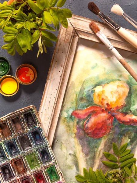 Brushes, acrylic and watercolor paints, a picture in a frame and a canvas, tools for the artist\'s creativity on a dark background in a vintage style