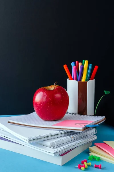 School accessories, notepad, pencils, markers, apple. Concept back to school on a blue background