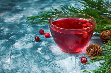 Ladin dalları ve koniler ile mavi mermer arka plan üzerinde bir cam bardak kızılcık meyveleri yapılan taze sulu içecek alanının bir kopyası ile