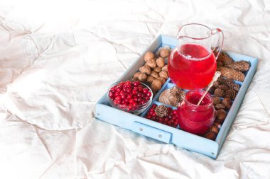 Kopya alanı ile beyaz bir battaniye üzerinde bir tepsi üzerinde bir tepsi üzerinde bir cam kase kızılcık, reçel ve çilek çilek meyve suyu içmek, sağlıklı sağlıklı kahvaltı ve tatlı kavramı 