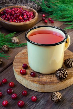 Ladin dalları ve soğuk ve ısınma tıbbi içecekler kopya alanı kavramı ile koniler ile koyu bir arka plan üzerinde bir demir fincan kızılcık suyu İçecek