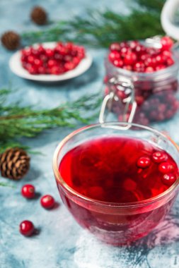 Ladin dalları ve koniler ile mavi mermer arka plan üzerinde bir cam bardak kızılcık meyveleri yapılan taze sulu içecek alanının bir kopyası ile