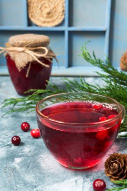 Ladin dalları ve koniler ile mavi mermer arka plan üzerinde bir cam bardak kızılcık meyveleri yapılan taze sulu içecek alanının bir kopyası ile