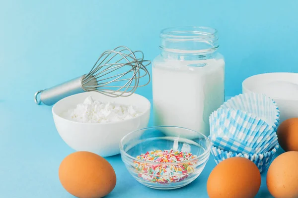 Eggs, flour, milk, sugar, and various ingredients for making pastry homemade pastry on a blue background with copy space
