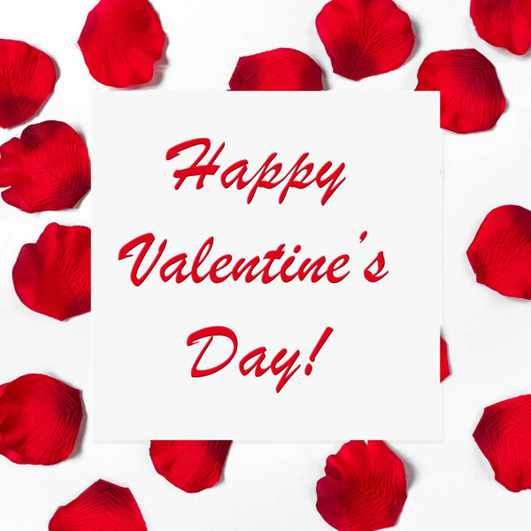 Rose petals on white background and the inscription of a happy Valentine's day on a white leaf in decorative pattern, the concept of a holiday card