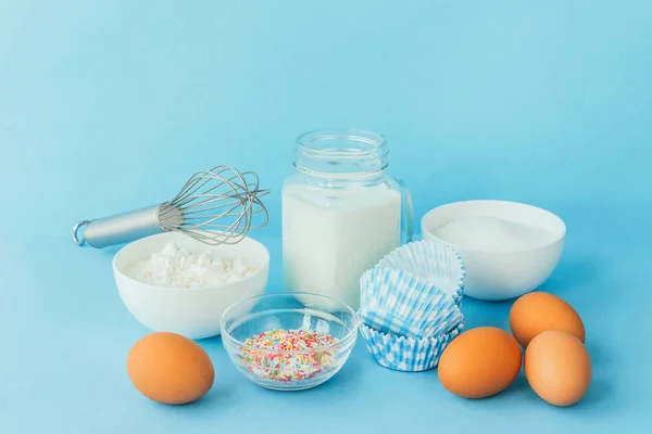 Eggs, flour, milk, sugar, and various ingredients for making pastry homemade pastry on a blue background with copy space