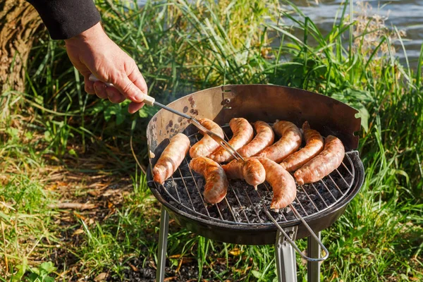 Grilled sausages on a barbecue grill during a summer picnic, the concept of recreation and tourism