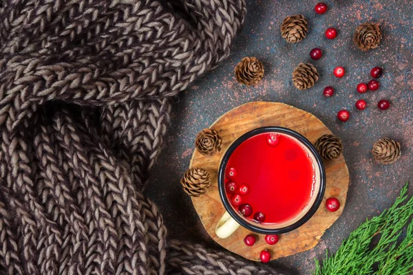 Drink juice from cranberries in an white cup on a dark background with spruce branches and cones with copy space concept of cold and warming medicinal drinks