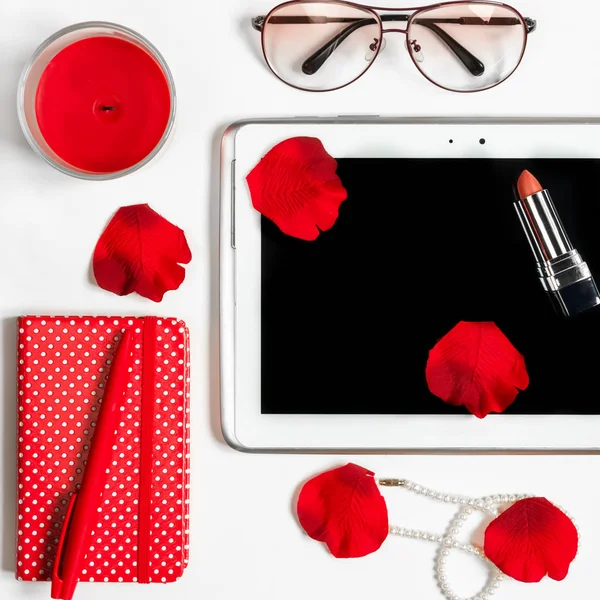 Not defteri, kalem, tablet, mum, kırmızı çiçek yaprakları ile beyaz arka plan üzerinde kırtasiye, kadın moda işyeri kavramı 