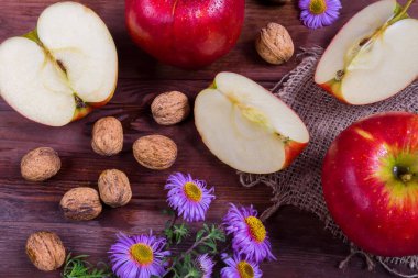 Kırmızı elma ve mor ve sarı çiçekler, bıçak ve ahşap bir arka plan üzerinde notlar dilimleri, sabah sonbahar günü atmosferi ve melodiler