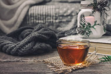 oturma odasında bir su ısıtıcısı ve ahşap bir masa, coziness kavramı üzerine bir kitap ile çay içme natürmort çay