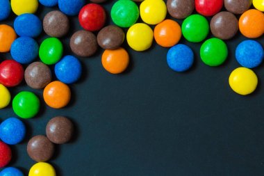 Koyu bir arka plan desen çerçeve arka plan üzerinde dragee şeklinde çok renkli tatlılar