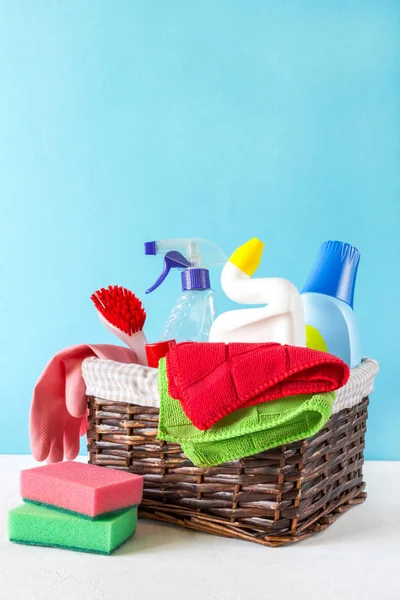 basket with a set of accessories for cleaning cleaning agents and rags and gloves. Empty space for text or logo on a blue background. The concept of cleaning service