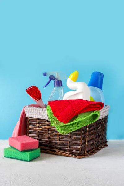basket with a set of accessories for cleaning cleaning agents and rags and gloves. Empty space for text or logo on a blue background. The concept of cleaning service
