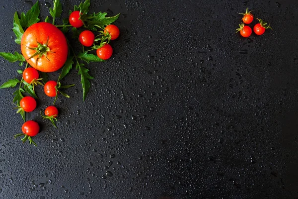 Fresh cherry tomatoes on a black background with spices.