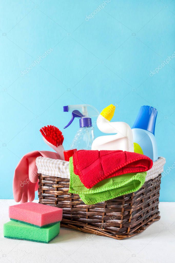 Basket with a set of accessories for cleaning cleaning agents and rags and gloves. Empty space for text or logo on a blue background. The concept of cleaning service