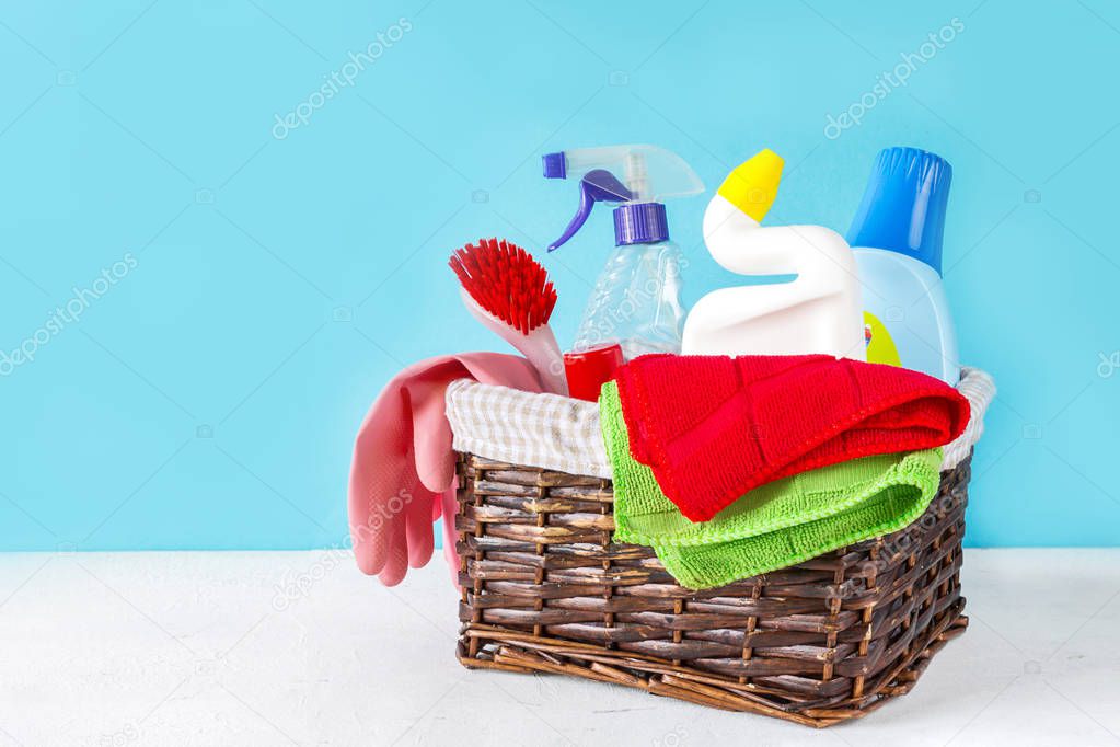 Basket with a set of accessories for cleaning cleaning agents and rags and gloves. Empty space for text or logo on a blue background. The concept of cleaning service