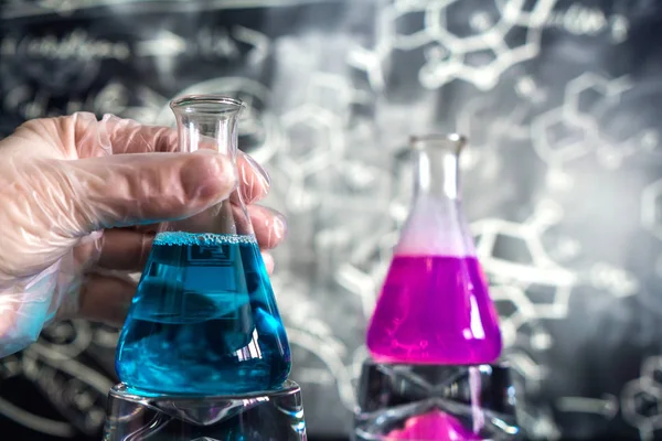 Laboratuvarın arka planına karşı reaksiyon sırasında renkli sıvı ile dolu bir kimyasal laboratuvarda cam, kimyasal deneyim, tıpta teknolojiler, ilaç