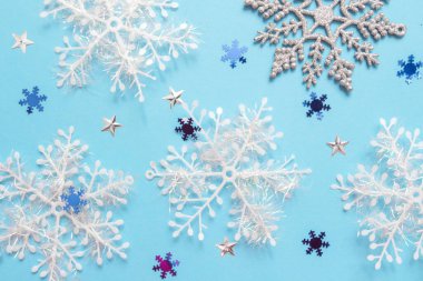 Mavi arka planda çok renkli kar tanelerinin olduğu bir Noel. Kış konsepti Yeni yıl tatili modeli