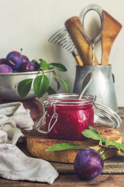 Cam kavanozdaki meyve kırmızısı erik reçeli ve kırsal mutfakta bir kasedeki böğürtlenler fotokopi alanı ile uyumlu klasik tarzda.