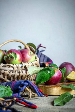 Hasır sepet içinde sulu olgun elmalar ve ahşap bir masa üzerinde mutfak gereçleri İskandinav tarzı arka planda, organik gıda konsepti, hasat, bahçıvanlık