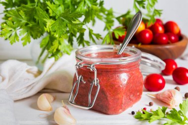 Tkemali sosu kırmızı eriklerden ve sarımsak, maydanoz, dereotu ve hafif ahşap arka planda fotokopi alanı olan biberlerden yapılır.
