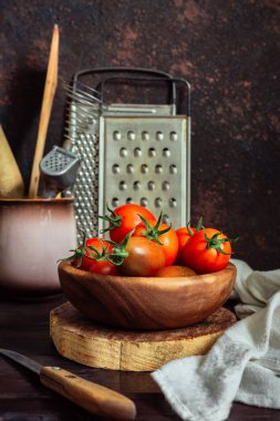 Taze domatesler, maydanoz, dereotu, sarımsak koyu bir arka planda, kırsal bir mutfakta ve ahşap çatallar.