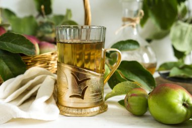 Bardakta elma çayı, sürahi ve olgun elmalarla dolu bir sepet eski usul ahşap bir masada.