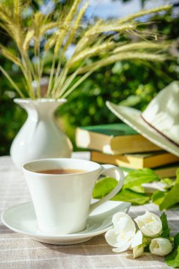 Bir bardak çay, bir laptop, bir bilgisayar, bir yaz sabahı bahçede bir kitap parlatma masası, çalışmak için bir yer, serbest çalışma konsepti.