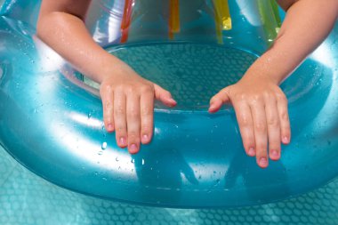 Suya yakın bir havuzda genç bir kızın eli. Su ve eğlence konsepti.