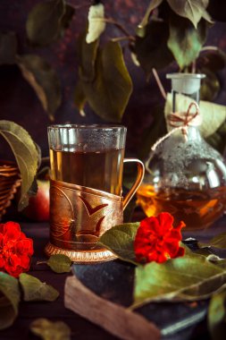 Bardakta elma çayı, sürahi ve olgun elmalarla dolu bir sepet eski usul ahşap bir masada.