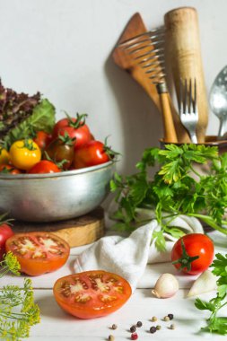 Taze domates, maydanoz, dereotlu sarımsak, arka planda hafif bir mutfak ve ahşap çatal bıçaklar fotokopi alanı olan yaşam.
