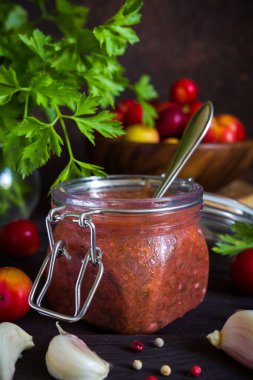Tkemali sosu kırmızı eriklerden ve sarımsak, maydanoz, dereotu, koyu ahşap arka planda fotokopi alanı olan biberlerden yapılır.