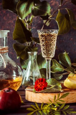 Bardakta elma şarabı, sürahi ve sepet içinde olgun elmalar eski usul ahşap bir masada.