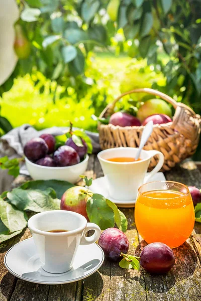 Lunch breakfast on the terrace in the garden. Orange juice, pie, coffee, tea, apples on a wooden table in the garden.
