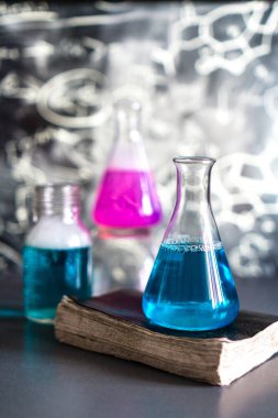 Laboratuvarın arka planına karşı reaksiyon sırasında renkli sıvı ile dolu bir kimyasal laboratuvarda cam, kimyasal deneyim, tıpta teknolojiler, ilaç