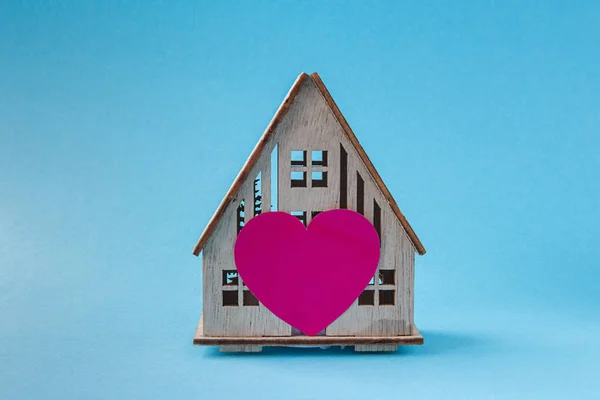 Holzhaus mit Herzkonzept der Familie, Liebe zu Hause, Komfort, Geschenk, Valentinstag auf pastellfarbenem Hintergrund — Stockfoto