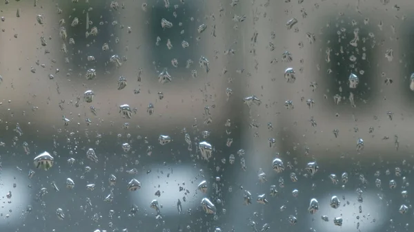 Large and small transparent raindrops on the window pane