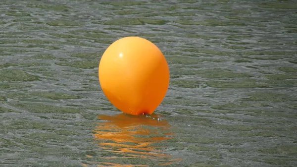 Orange balloon floats on the dark water