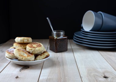 Ekşi krema ile beyaz bir plaka üzerinde süzme peynir krep. Ahşap
