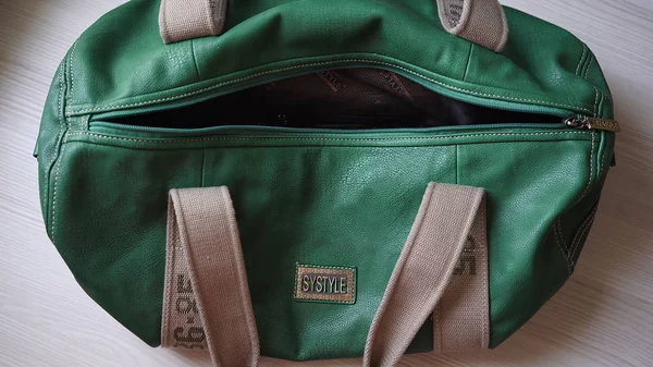 green travel bag made of soft leather, unbuttoned, top view
