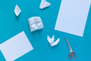 temiz beyaz kağıt, makas, origami kağıt: uçak, tekne ve tilki mavi bir arka plan, üst görünümü