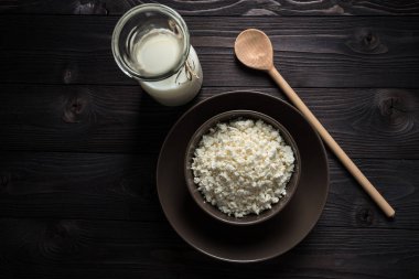 koyu ahşap arka plan üzerinde kahverengi bir kapta süzme peynir